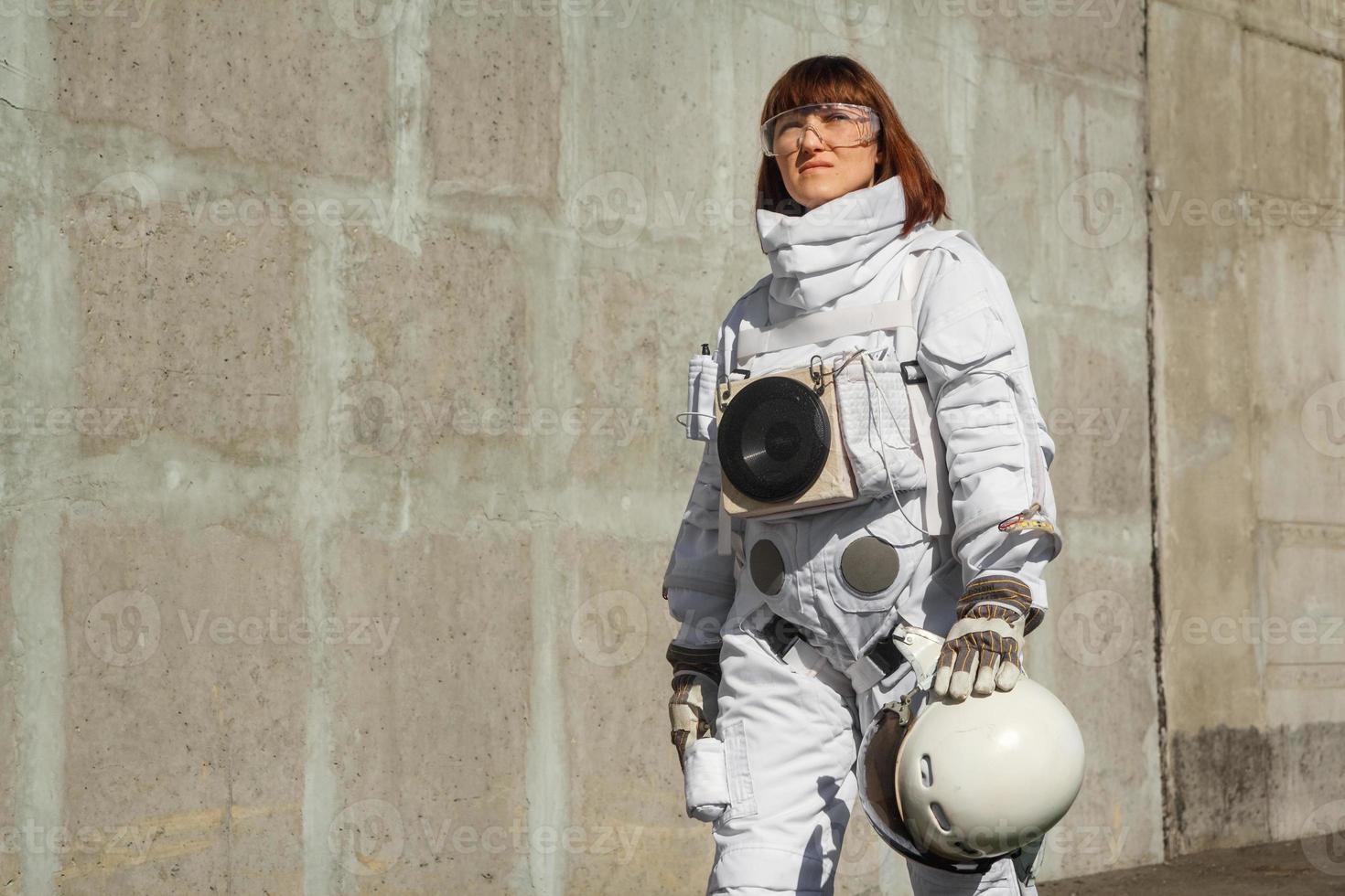 Woman astronaut without a helmet on the background of a gray wall photo
