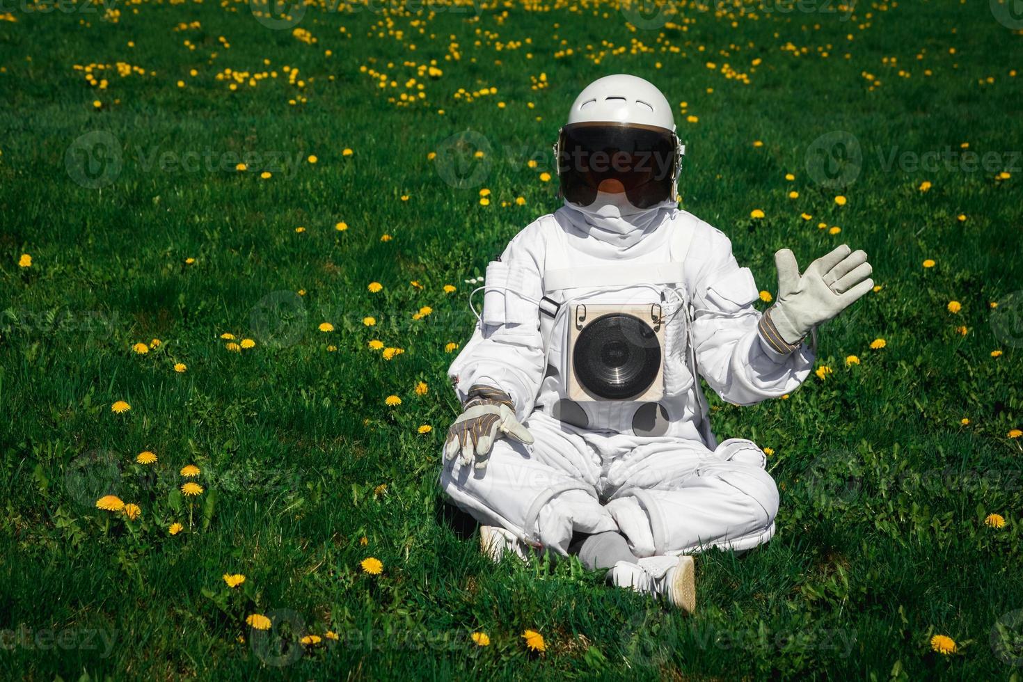 Astronauta futurista en un casco se sienta en un césped verde entre flores foto