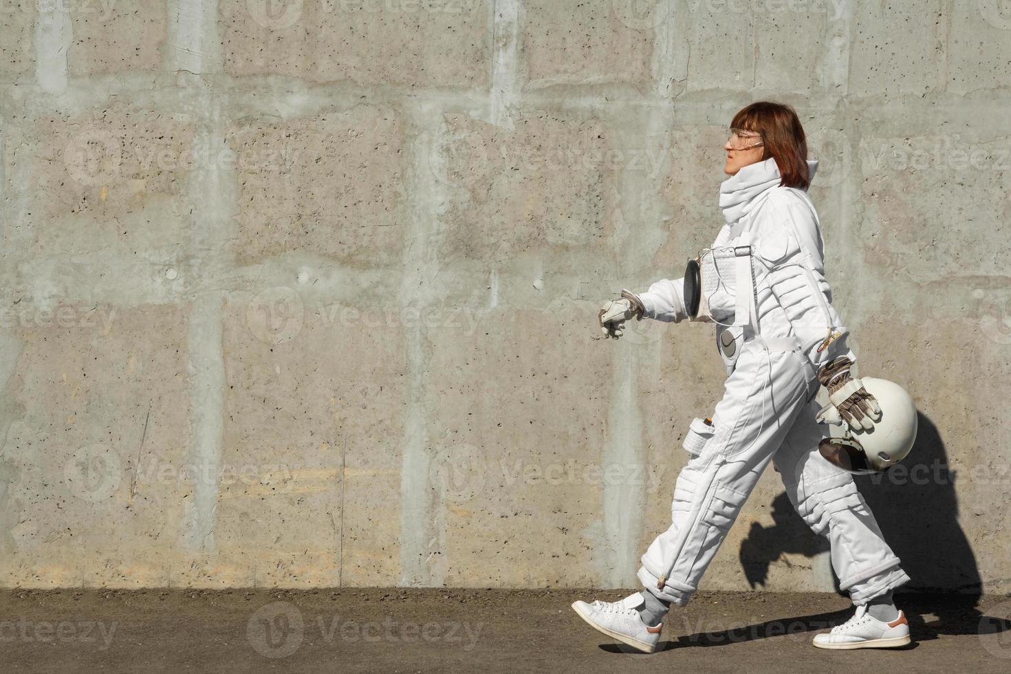 Mujer astronauta sin casco en el fondo de una pared gris foto