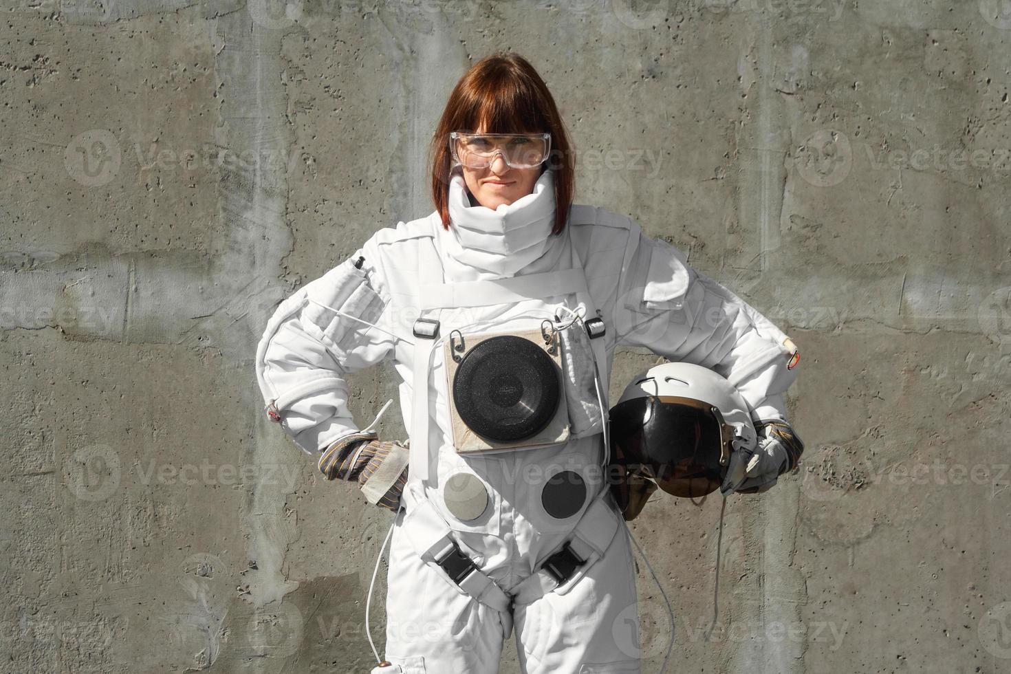 Woman astronaut without a helmet on the background of a gray wall photo