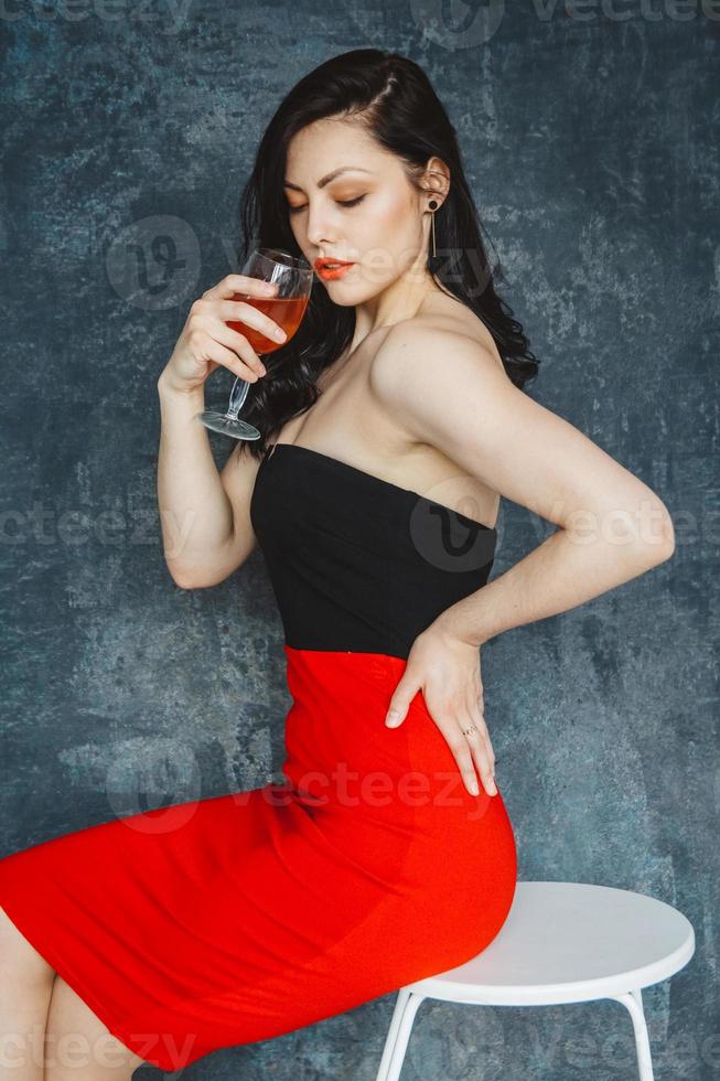 Beautiful young woman with glass of wine on gray background photo