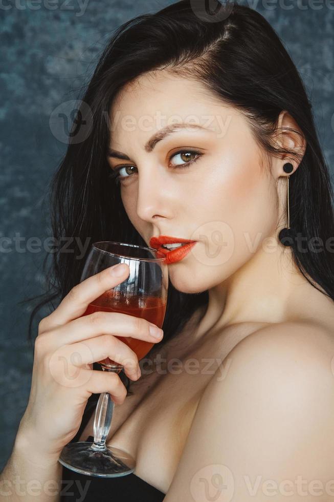 Hermosa mujer joven con copa de vino sobre fondo gris foto