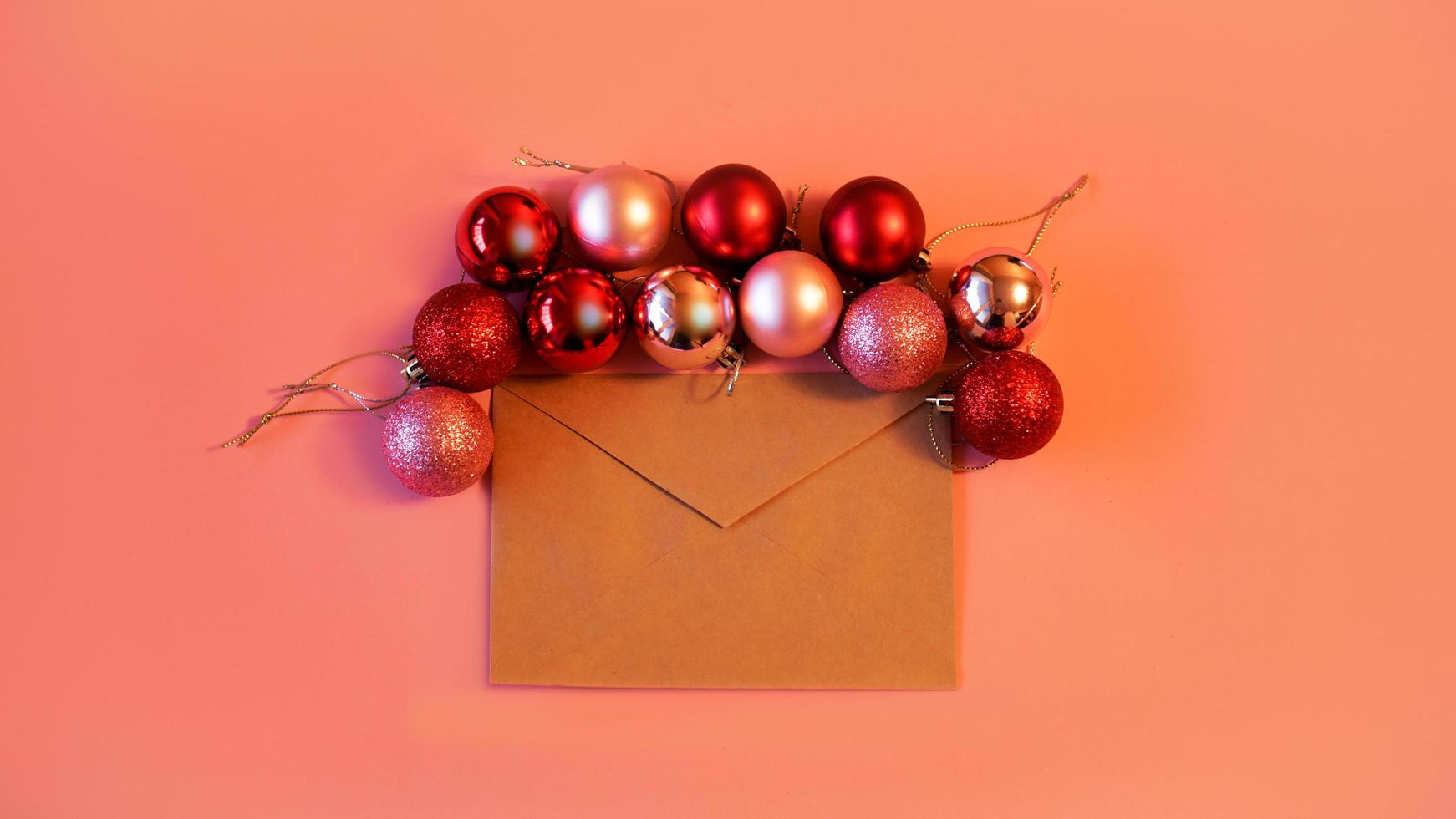 Envelope from craft paper with christmas red and pink balls on pink photo