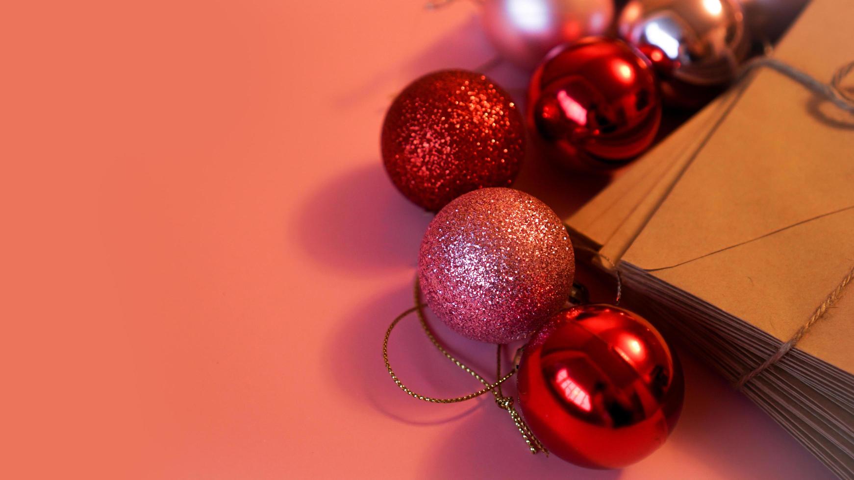 pila de cartas de papel artesanal con bolas navideñas rojas y rosas foto