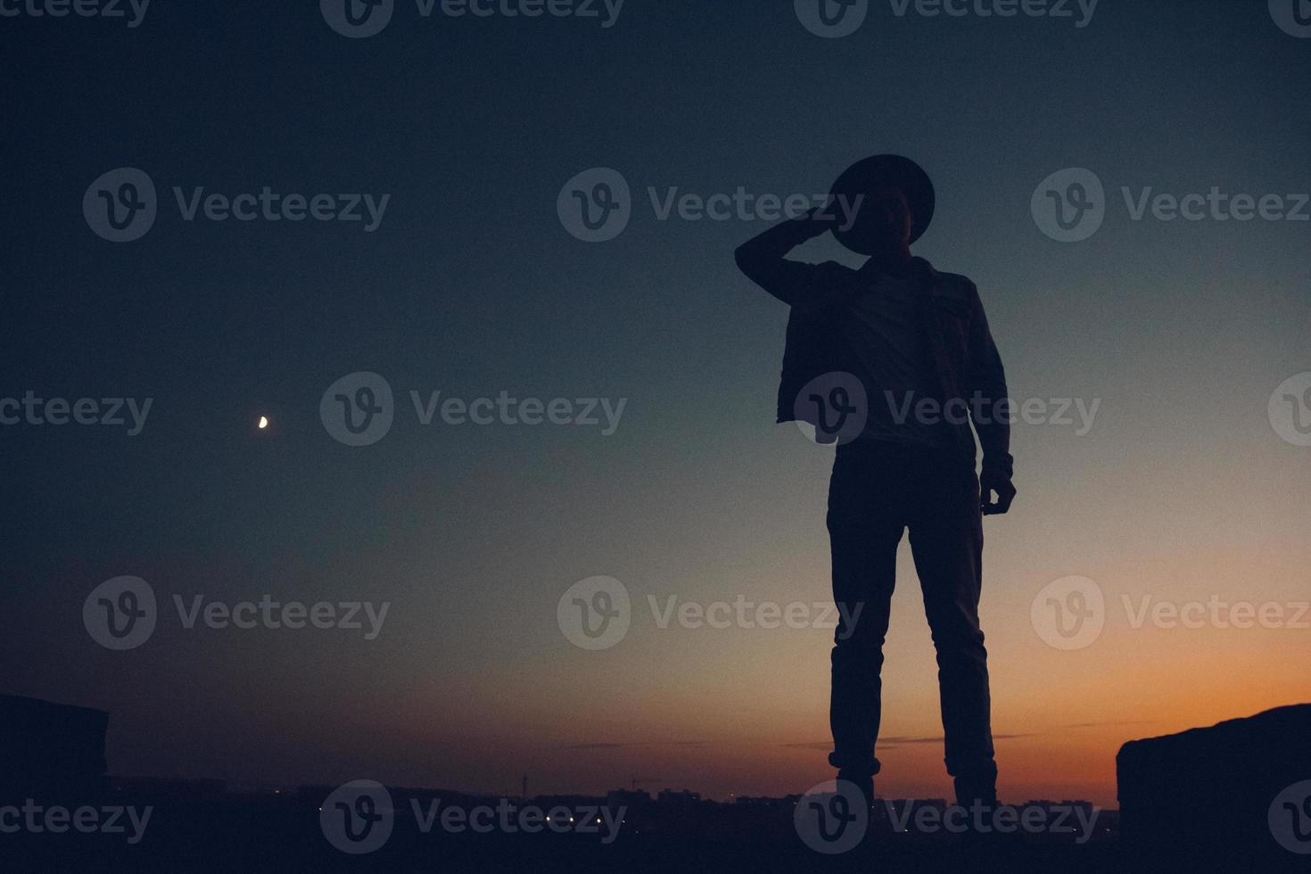 Silhouette of a man watching the sunset over the city photo