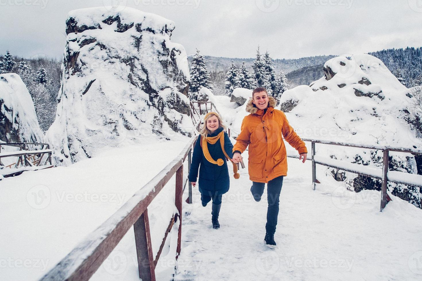 chico y chica caminan y se divierten en el bosque en invierno foto