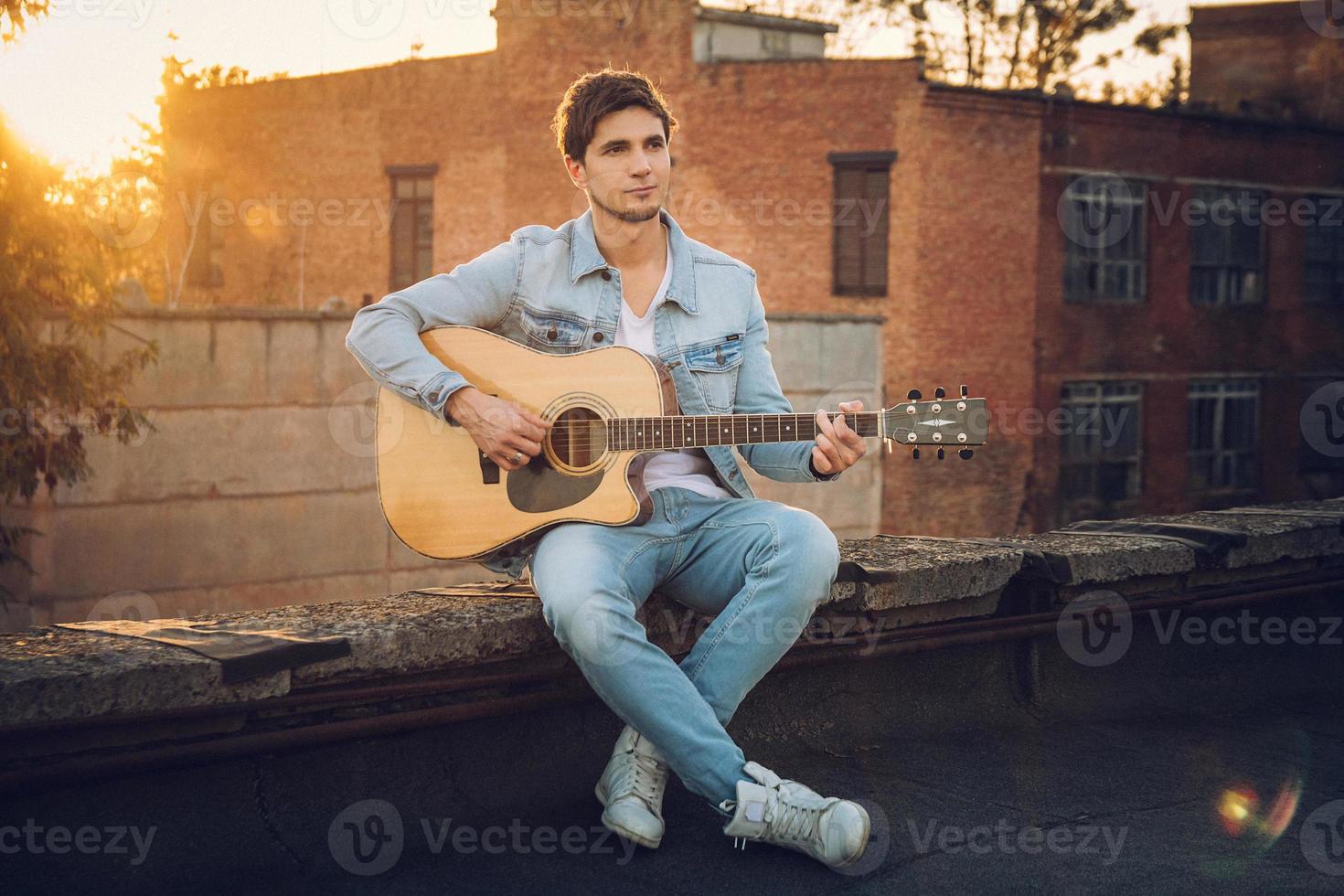 Young man playing guitar in city on sun rays background photo