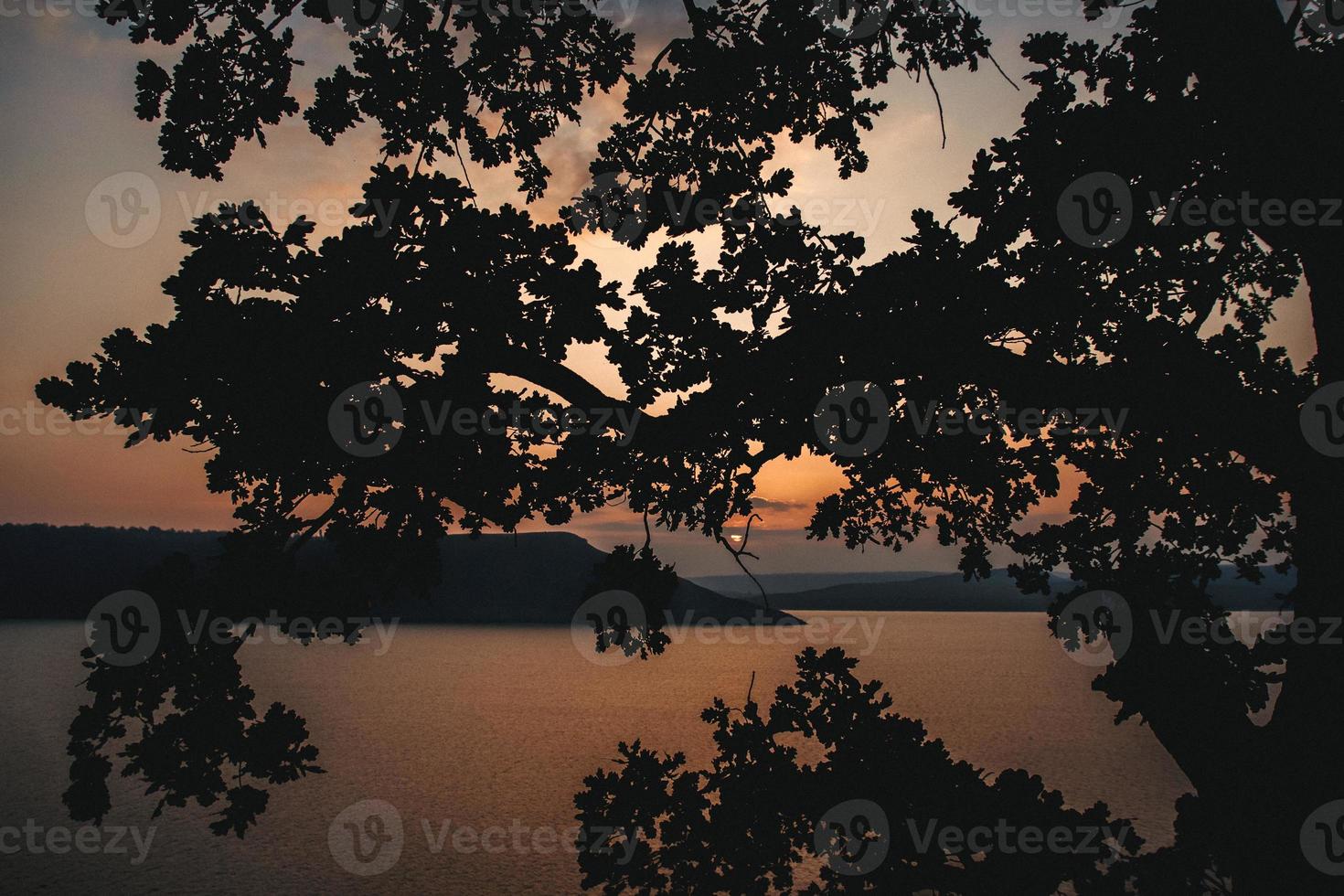 majestuosa puesta de sol en el paisaje de las montañas sobre un lago tranquilo foto