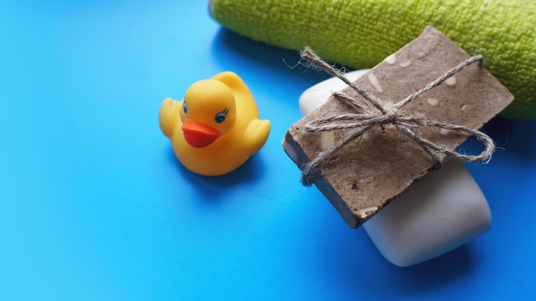 Towel, soap and yellow toy duck on a blue background photo
