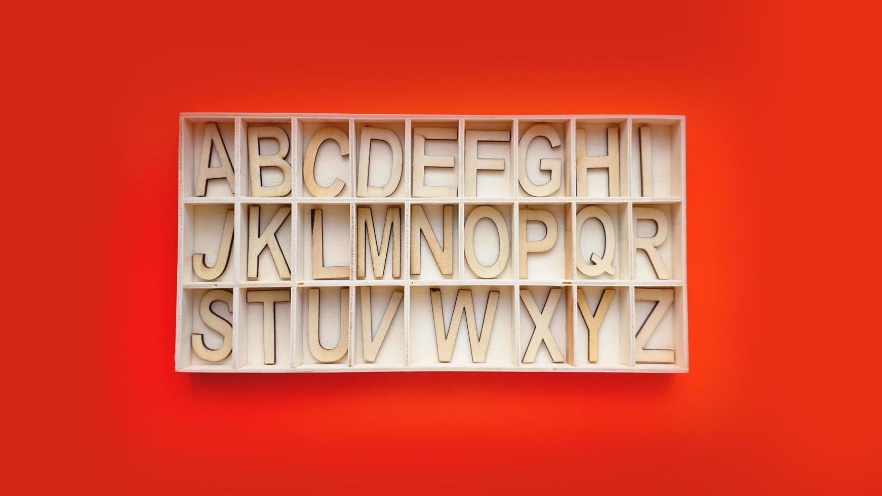 Wooden alphabet blocks with letters - box on a red background photo