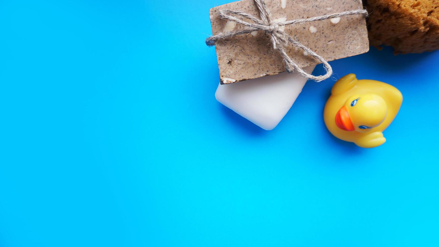 Handmade soap and yellow toy duck on a blue background photo