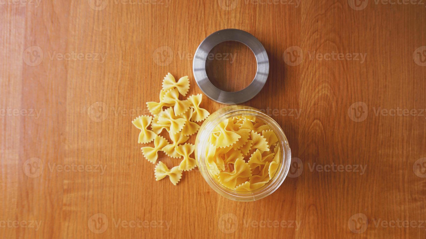 Pasta in the form of bows scattered from glass jar photo