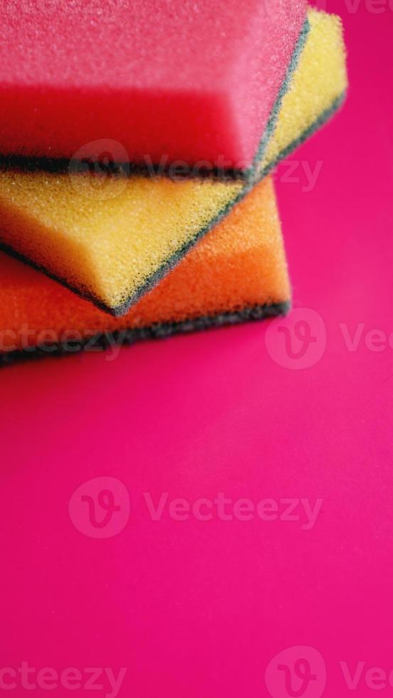 Household cleaning concept. Colorful sponges on pink background photo