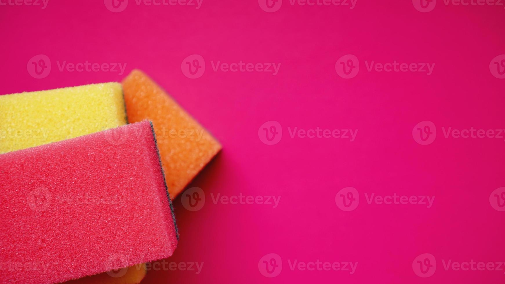 Household cleaning concept. Colorful sponges on pink background photo