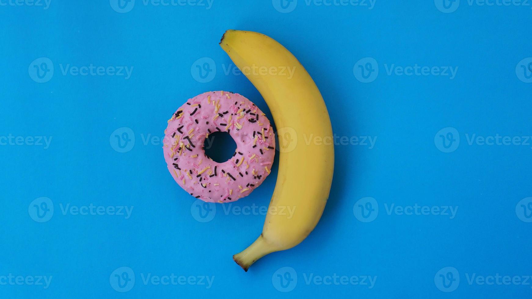 Donut dulce y plátano sobre fondo de color azul foto