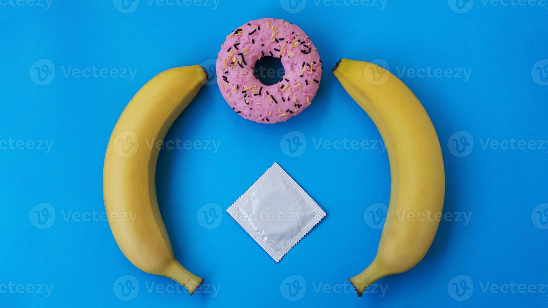 Two bananas and a pink donut on blue background photo