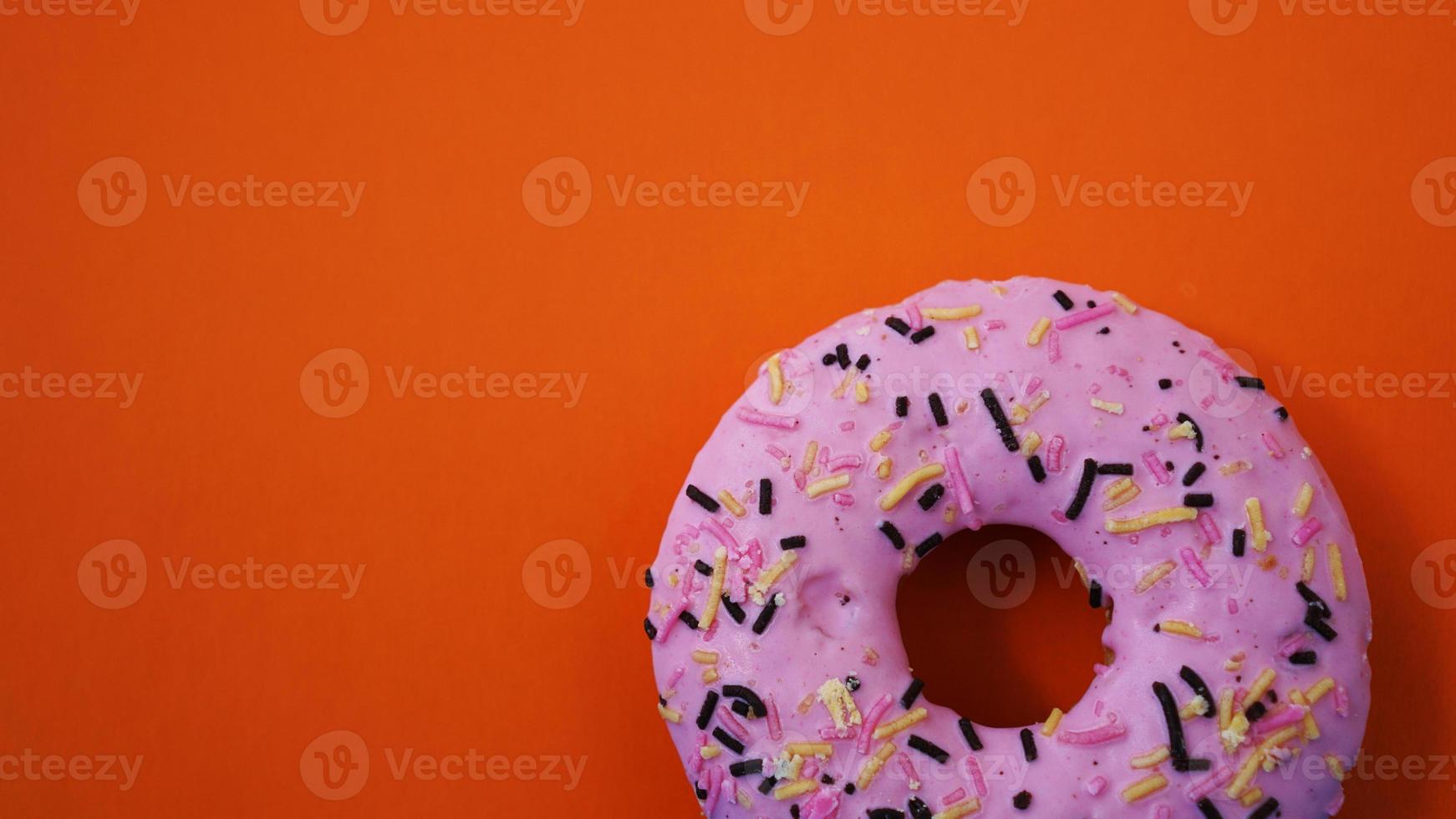 Sweet pink donut on orange background photo