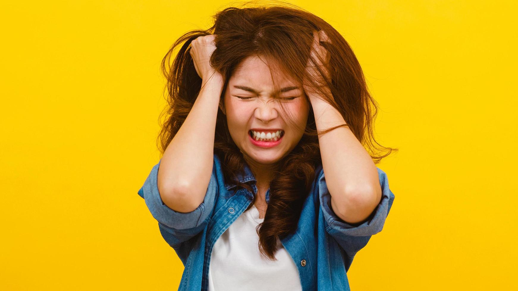 Asian female with negative expression over yellow background. photo