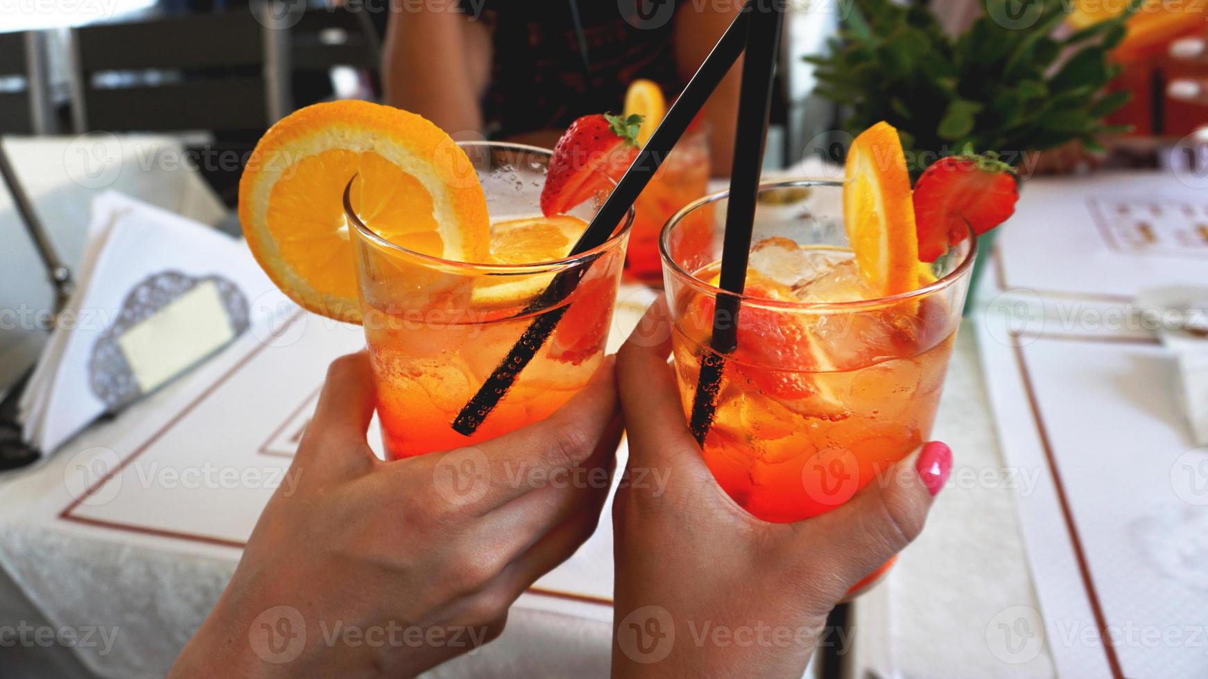 Joven pareja alegre bebiendo cóctel aperol spritz en cafe foto