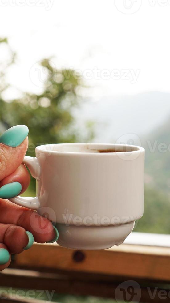 mano taza blanca de café caliente. por la mañana, frías vistas a la montaña foto