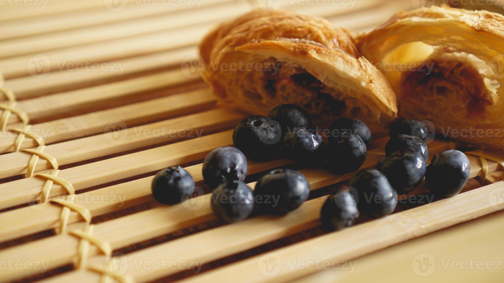 Delicioso desayuno con croissant y arándanos sobre fondo de madera foto