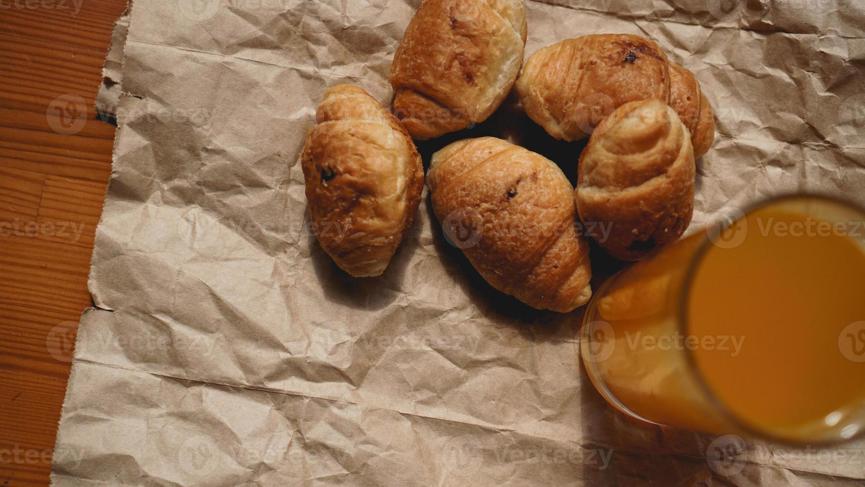 Croissants recién horneados con jugo de naranja sobre papel kraft foto