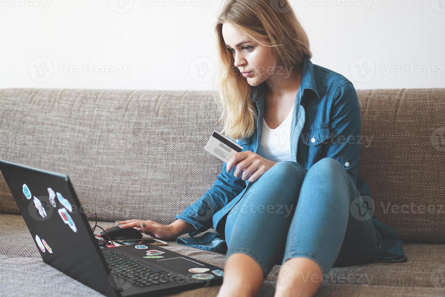 Mujer bonita joven que trabaja con un portátil y una tarjeta de crédito en casa foto