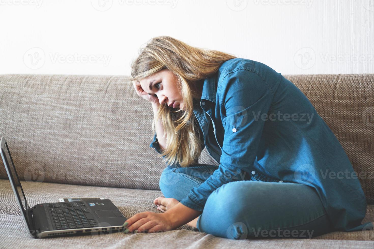 Mujer cansada sentada con un portátil, estudiante perezoso haciendo los deberes foto