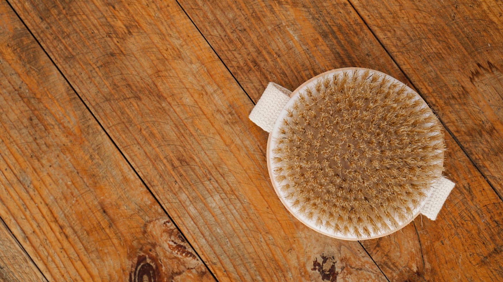 Cepillo de masaje seco hecho de materiales naturales sobre un fondo de madera foto