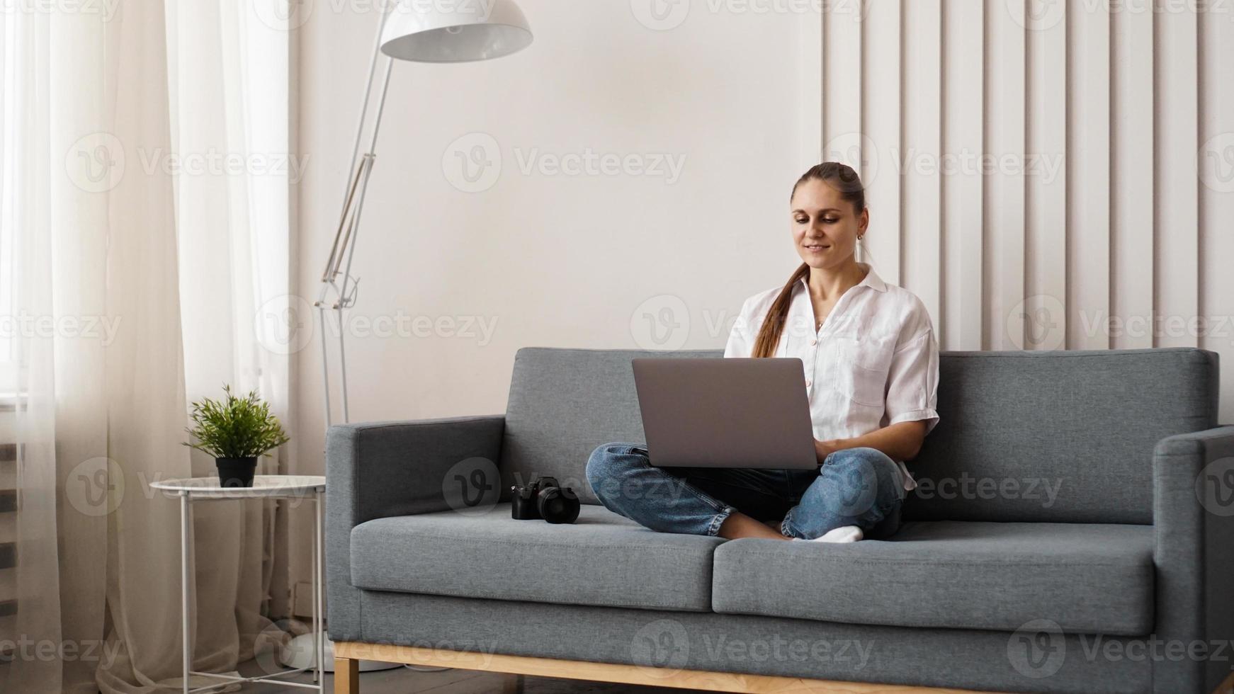 Happy young woman using laptop at home photo