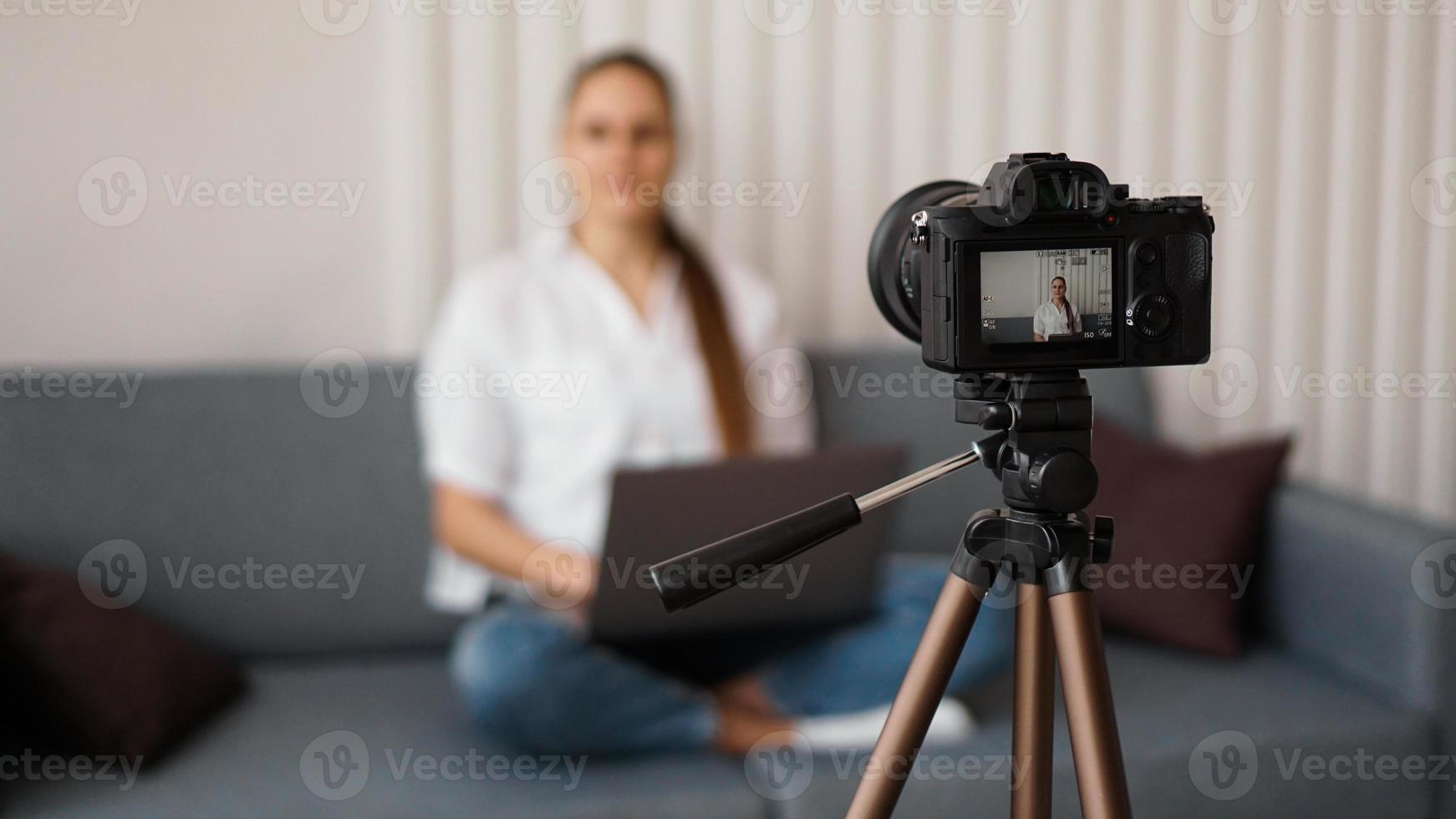 Blogger recording video indoors, selective focus on camera display photo