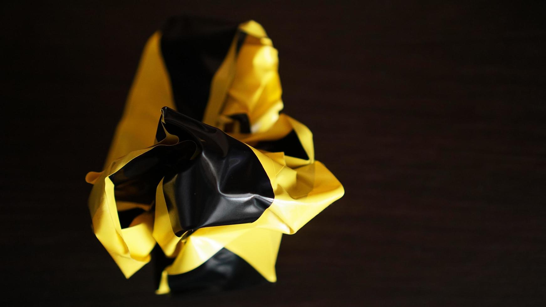 Crumpled yellow and black tape on dark background photo