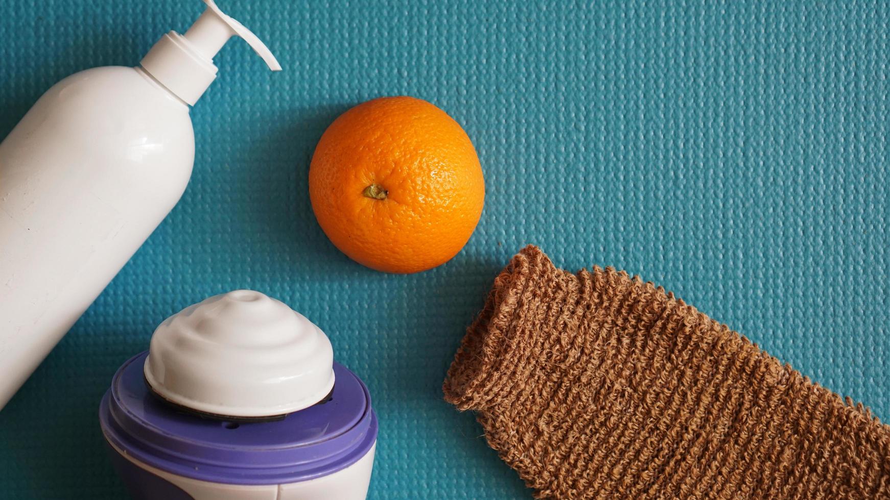 loción, naranja, esponja de ducha y masajeador anticelulítico foto