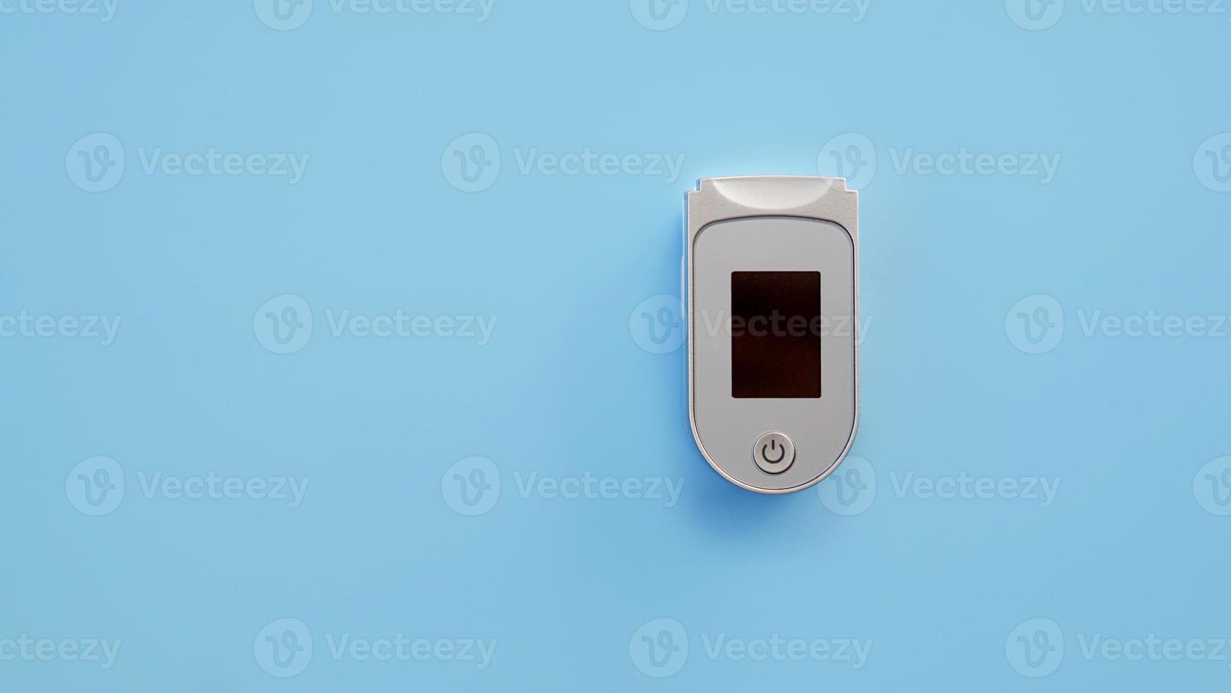 Portable Pulse oximeter isolated on blue background. photo