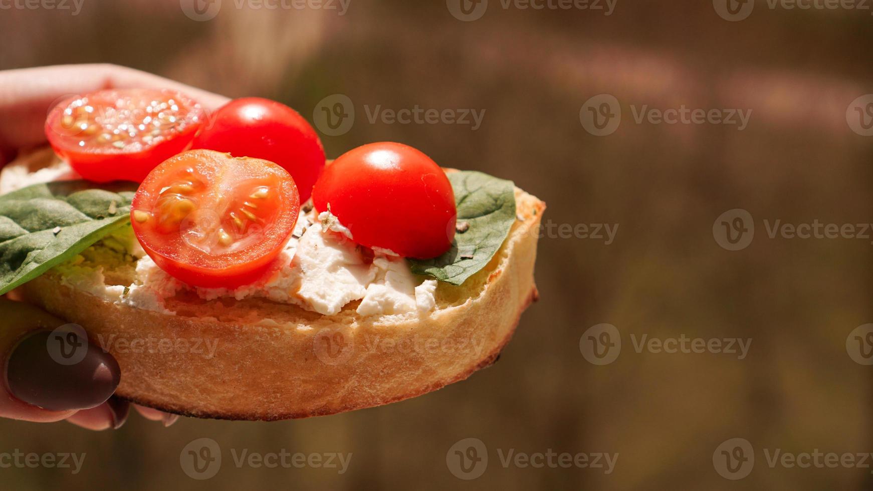 mano de mujer con bruschetta de tomate cherry. aperitivo de vino italiano foto