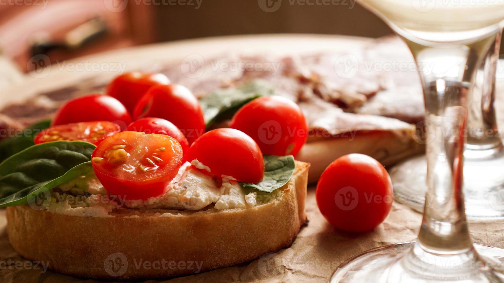 Bruschetta with cherry tomatoes. Wine glass, Italian appetizer. photo