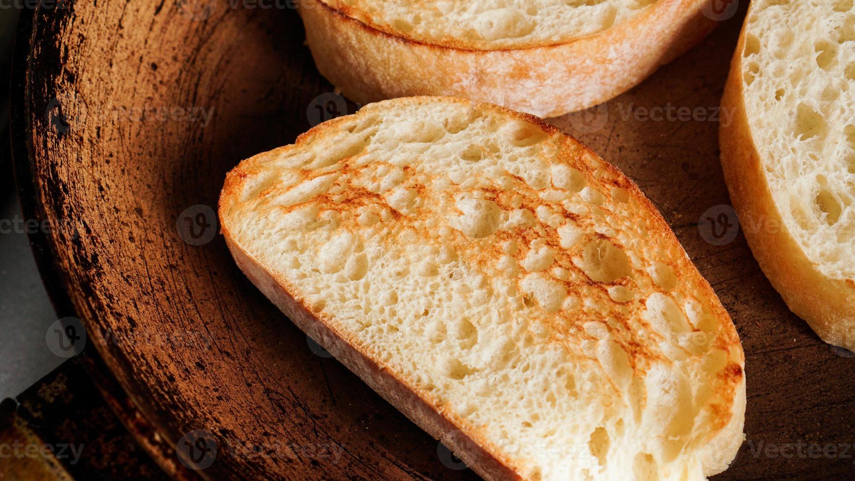 Sliced ciabatta is fried in a pan. Slice for bruschetta or breakfast. photo