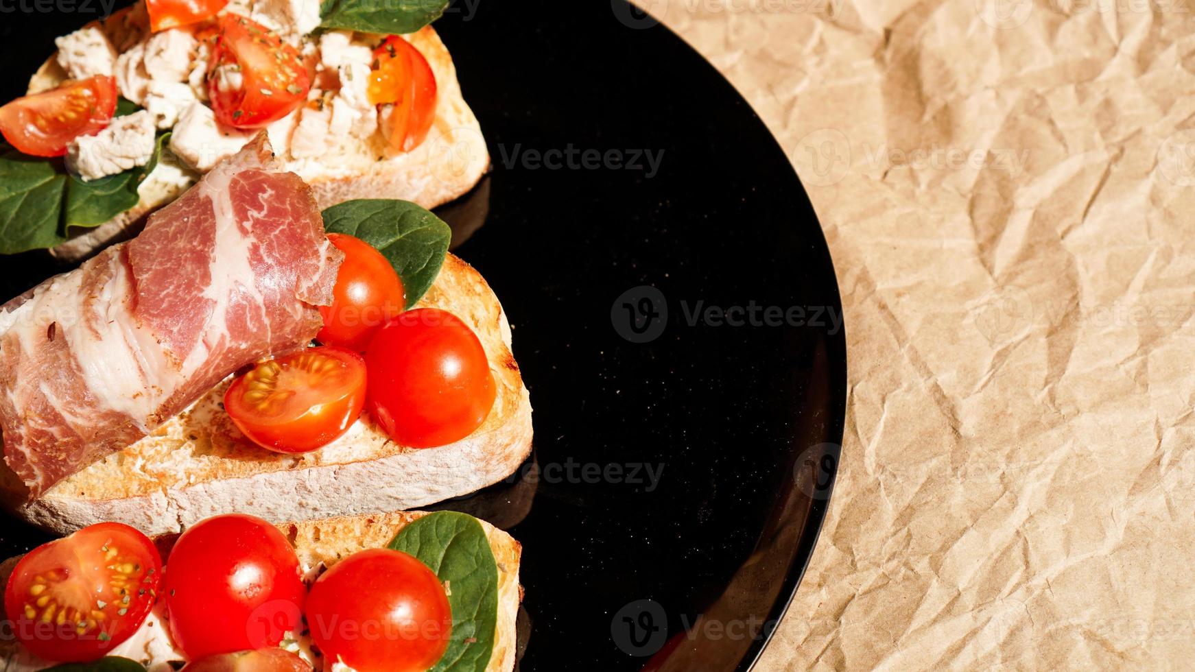 Three bruschetta on a black plate on craft paper photo