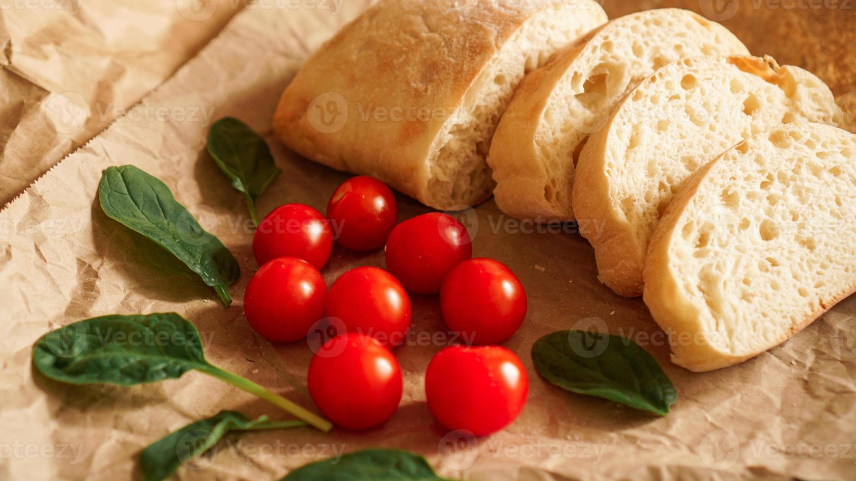 Ciabatta slices and cherry tomatoes on craft paper. photo