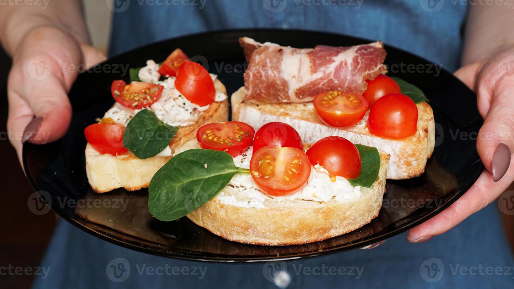 Woman waiter holding a wooden tray with bruschetta in her hand photo