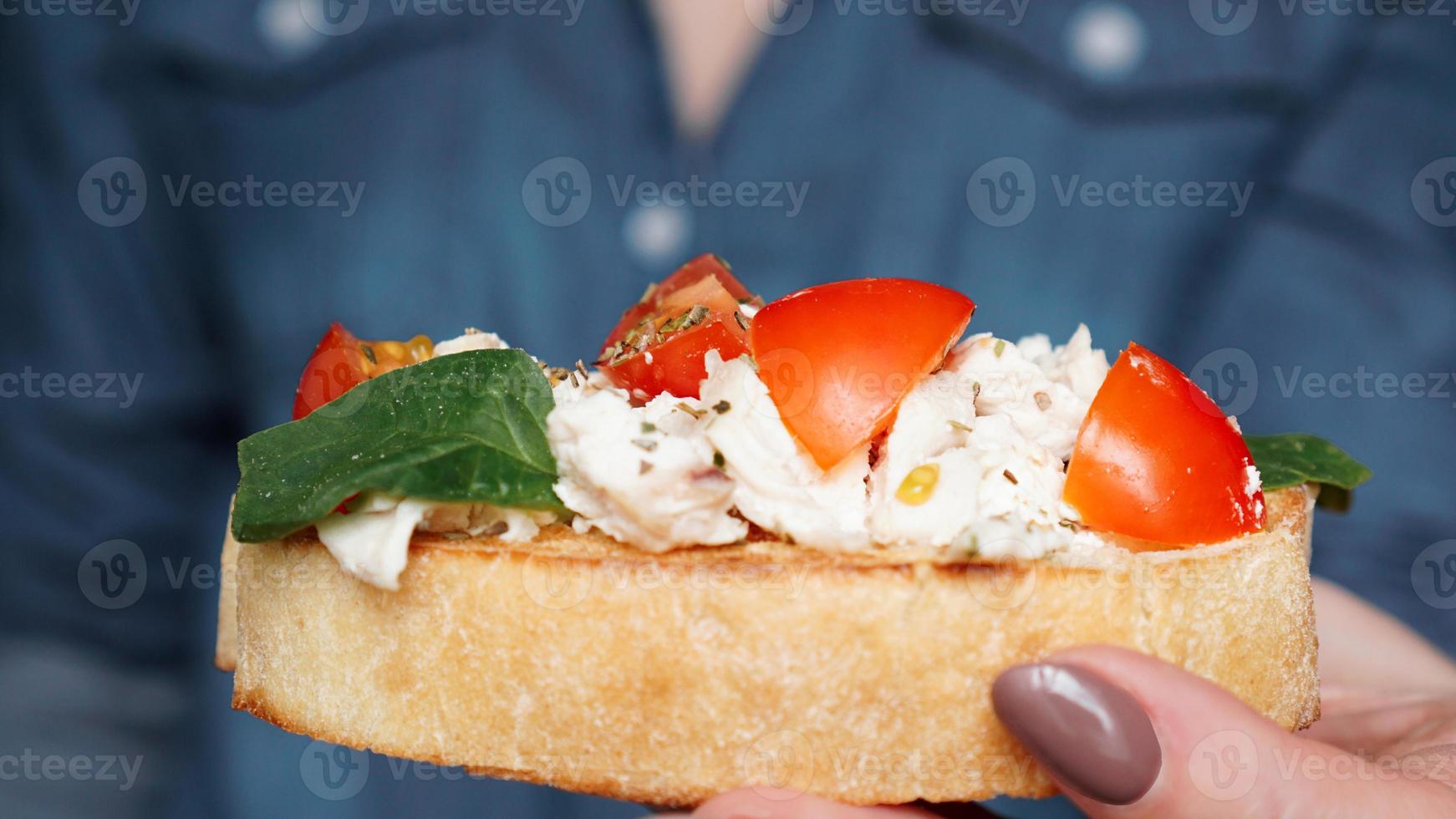 mano de mujer con bruschetta de tomate cherry. aperitivo de vino italiano foto