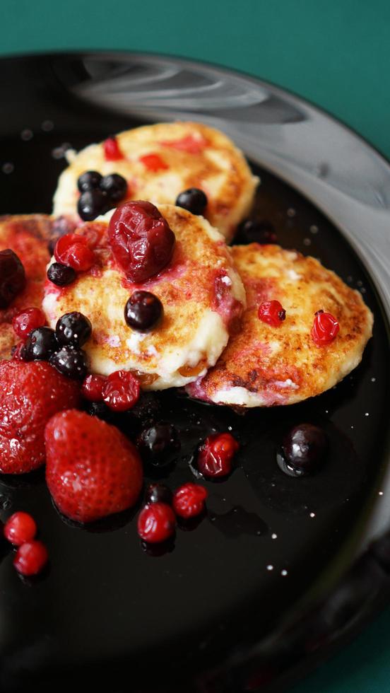 Cheese Pancakes with berries on a black plate. photo