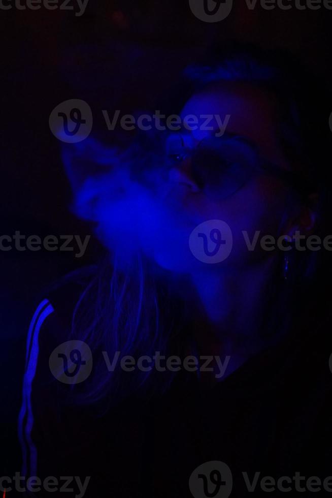 Close Up retrato de chica vaping en luz azul neón foto