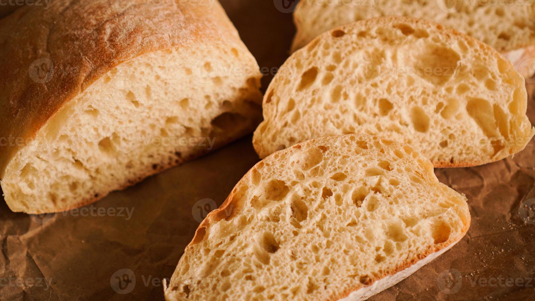 rodajas de ciabatta sobre papel artesanal. deliciosos pasteles frescos. foto