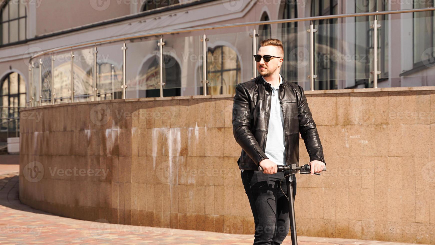 Modern man riding electric scooter in the city photo