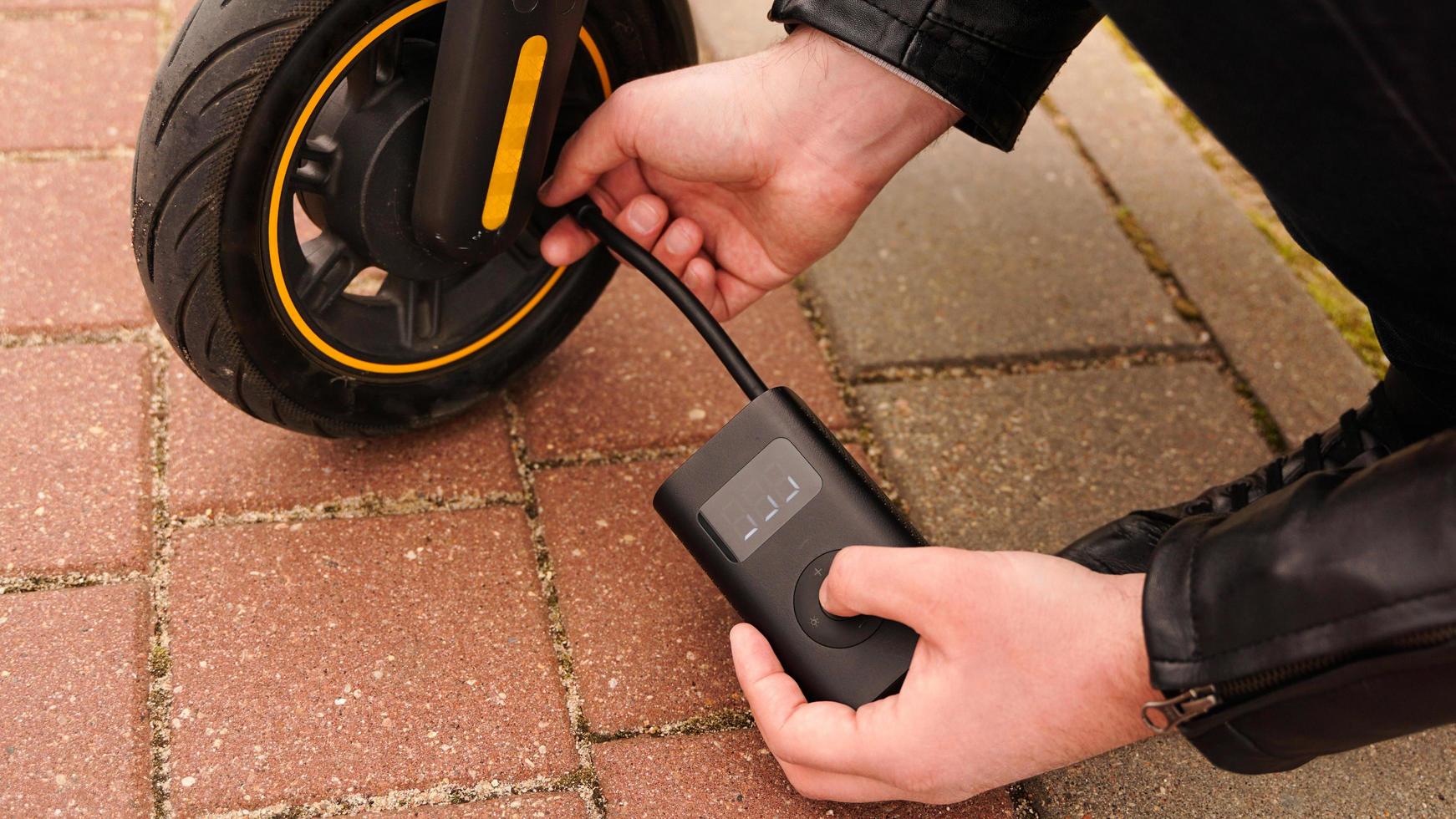 A man pumps air into the wheel of an electric scooter photo