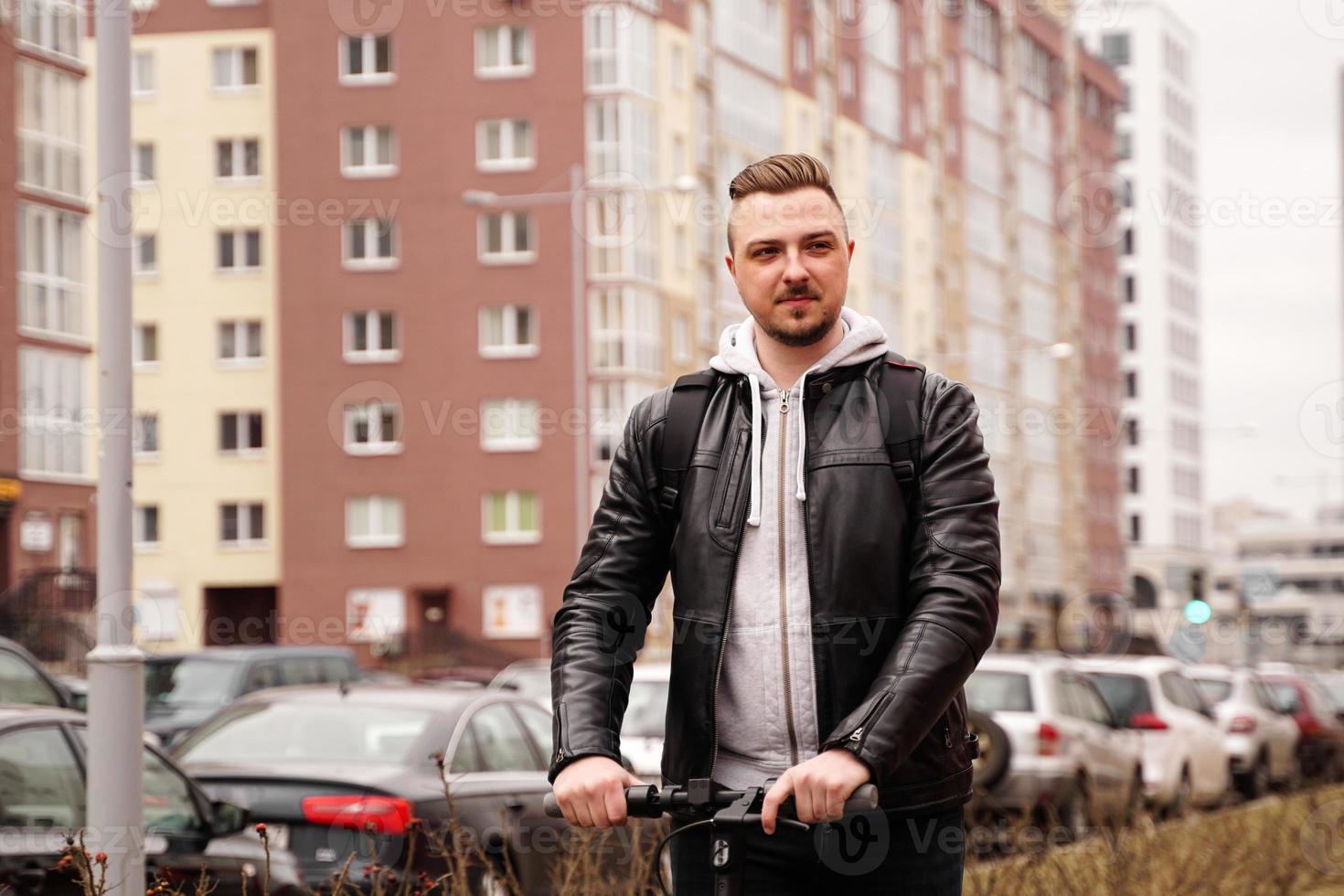 Hombre moderno montando scooter eléctrico en la ciudad foto