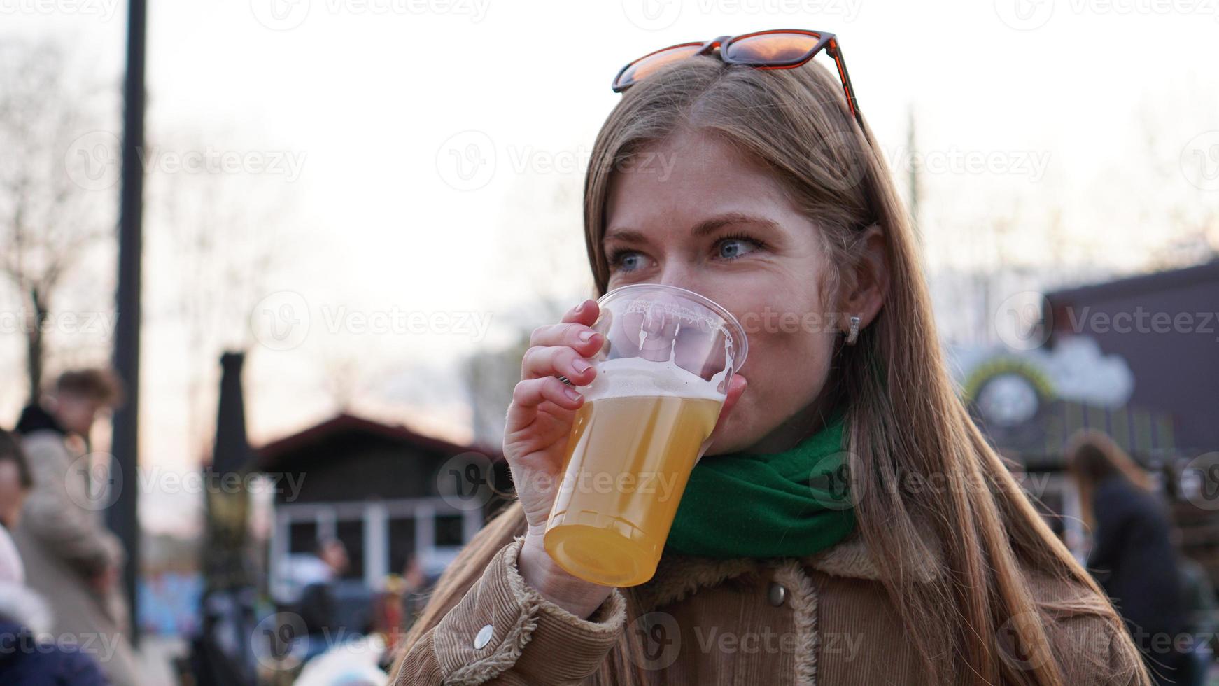 mujer joven bebe cerveza ligera. comida callejera y patio de comidas. foto