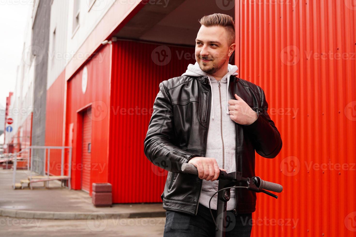 Young attractive man on electric scooter over red background photo