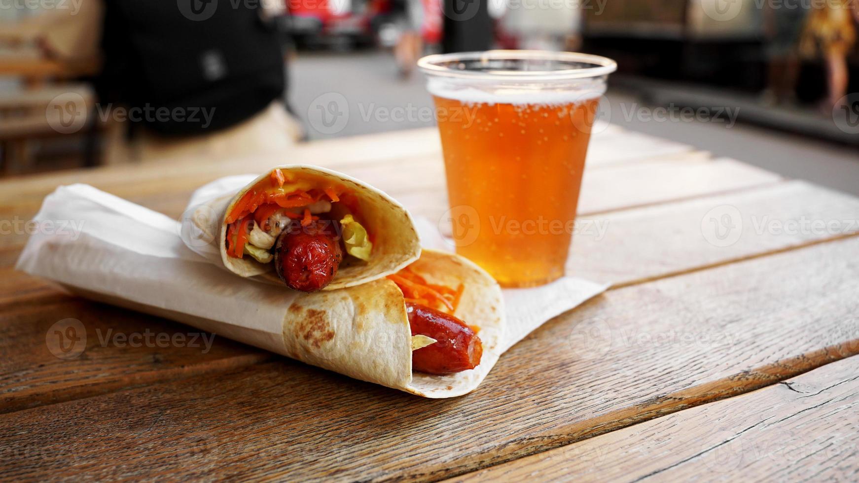 hot dog en pan de pita sobre una mesa de madera. comida de la calle foto